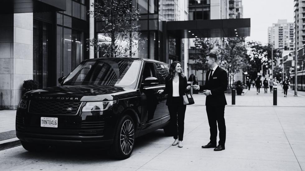 Professional valet attendant assisting a guest arriving in a luxury Range Rover outside a modern downtown Toronto building, showcasing premium valet parking service and seamless event arrival experience.